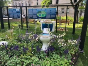 Art installation of a toilet with flowers on it in public garden